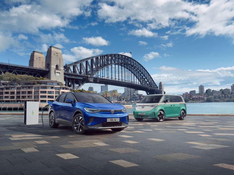 Blue VW car and green VW campervan by Sydney Harbour Bridge